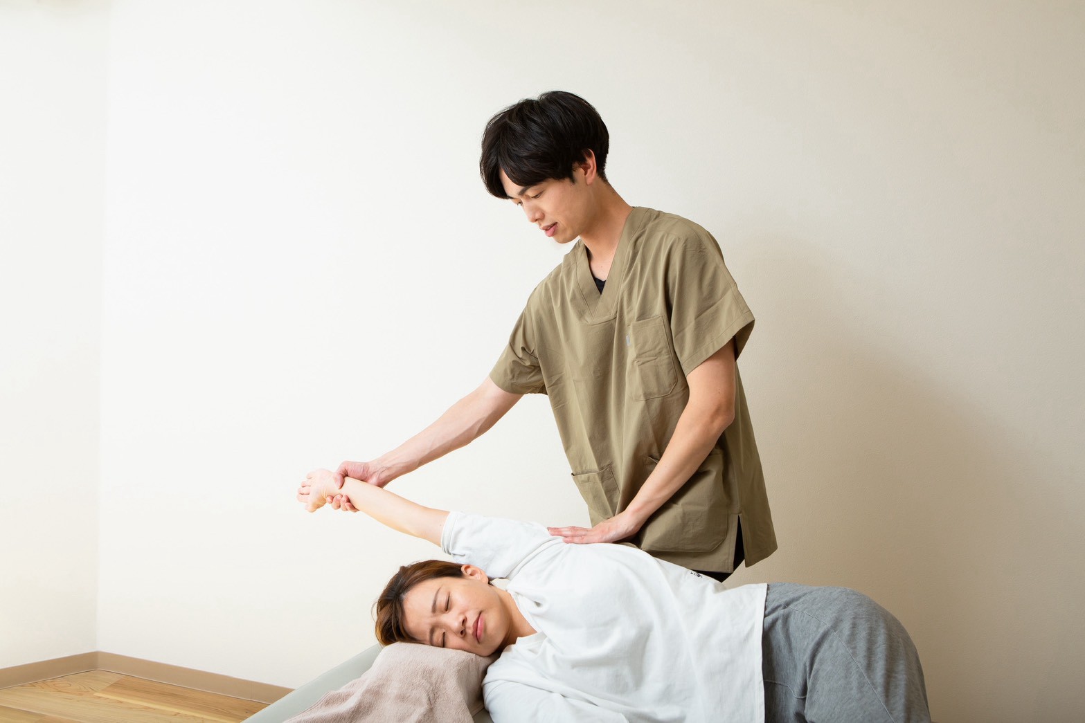 院長が、お客様の腕を上げて肩まわりを整えている様子