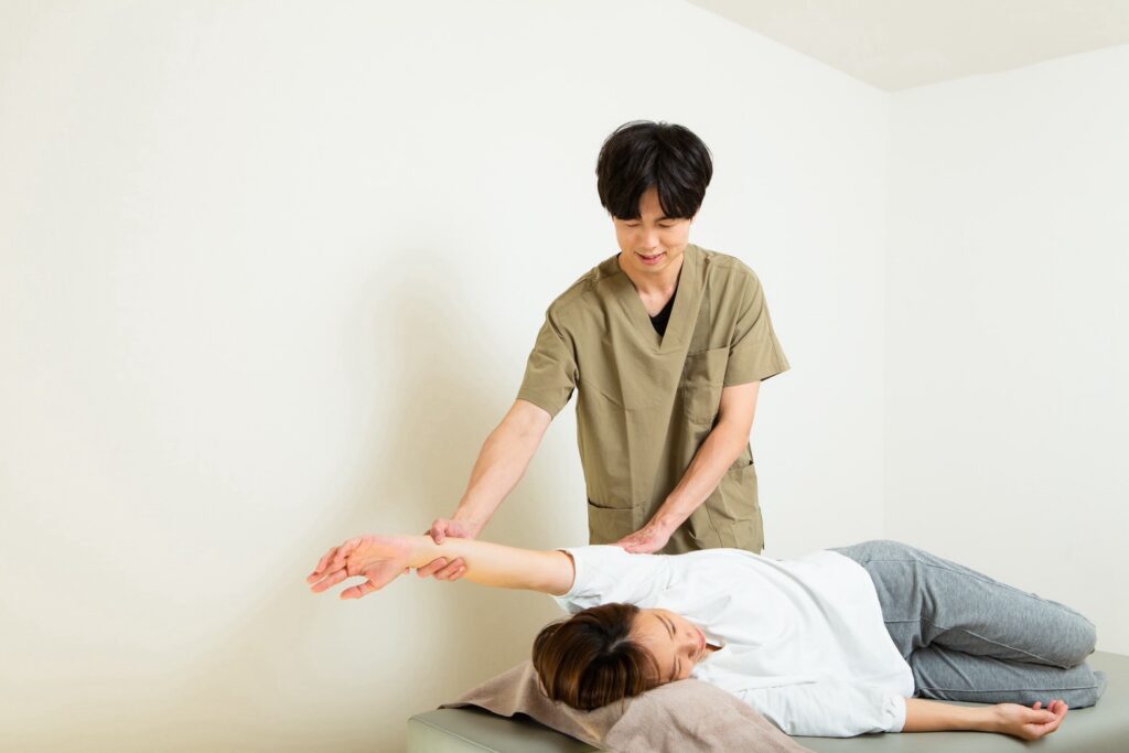 横向きの姿勢で腕まわりをやさしく動かす施術